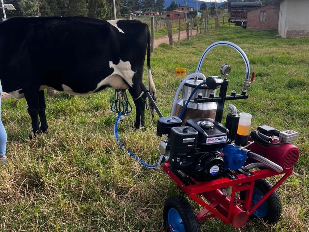 Equipo de ordeño Zan Car de deOrdeño ordeñando una vaca Holstein en el potrero